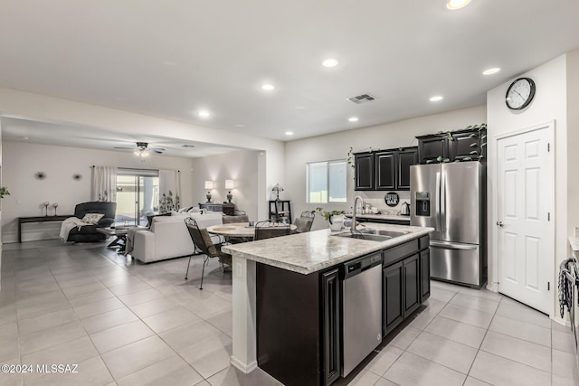 kitchen featuring ceiling fan, sink, stainless steel appliances, a center island with sink, and light tile patterned floors