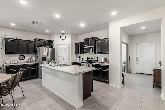 kitchen featuring appliances with stainless steel finishes, a center island with sink, light tile patterned floors, and sink