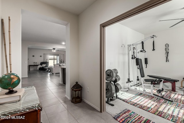 exercise room with ceiling fan and light tile patterned floors