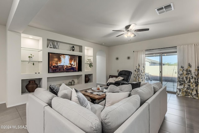 tiled living room with built in shelves, a water view, and ceiling fan