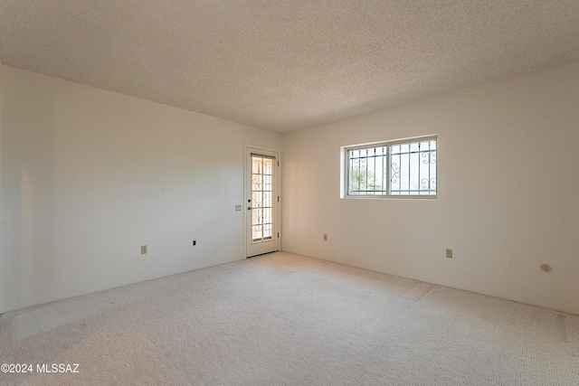 carpeted empty room featuring a textured ceiling