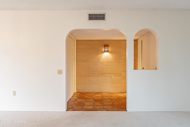 hallway with a textured ceiling and dark tile patterned floors