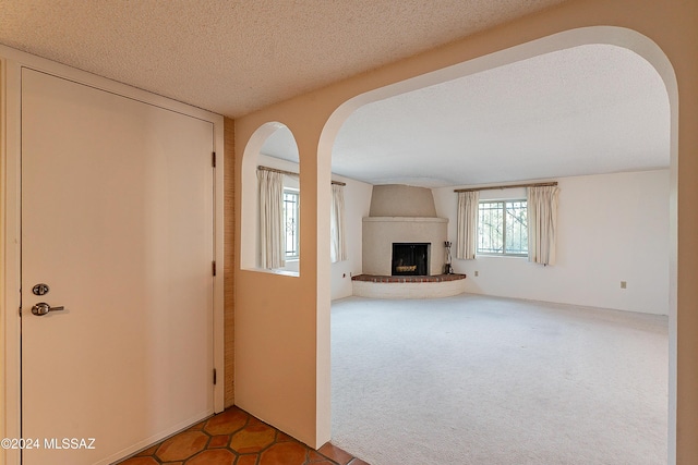 unfurnished living room with a fireplace, carpet, and a textured ceiling