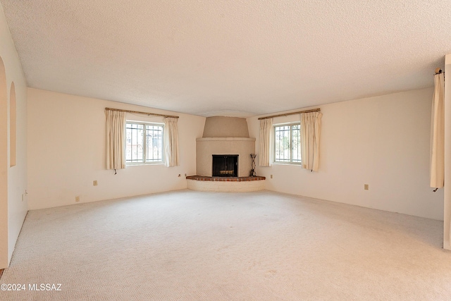 unfurnished living room featuring carpet flooring, a large fireplace, and a textured ceiling