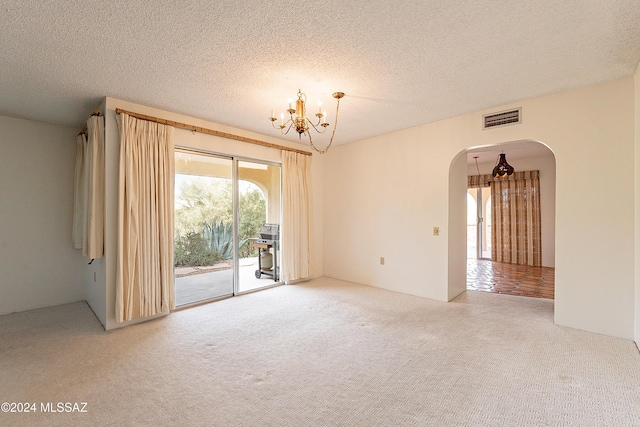 unfurnished room with carpet floors, a textured ceiling, and an inviting chandelier