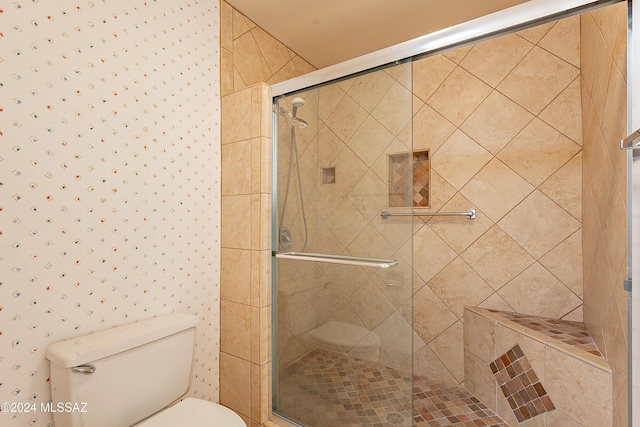 bathroom featuring toilet and a shower with shower door