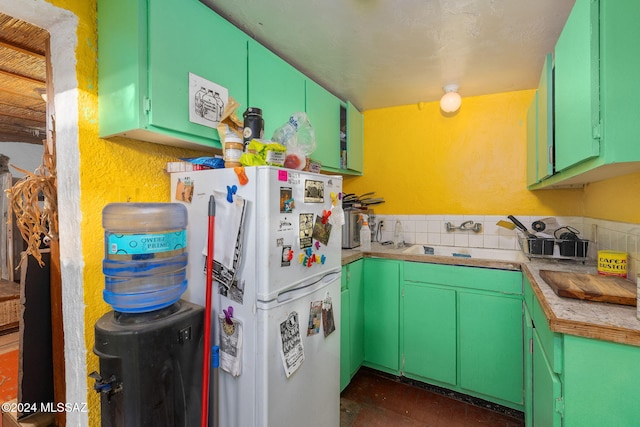 kitchen with sink, white fridge, and green cabinetry