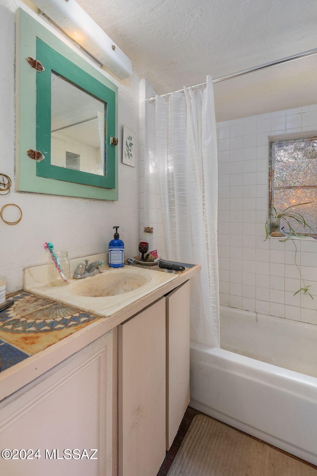 bathroom featuring vanity, shower / bathtub combination with curtain, and a textured ceiling