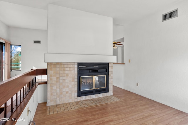 unfurnished living room featuring ceiling fan, a tile fireplace, and light hardwood / wood-style flooring