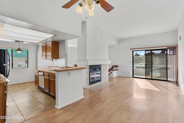 kitchen with black fridge, white dishwasher, ceiling fan, pendant lighting, and light hardwood / wood-style floors