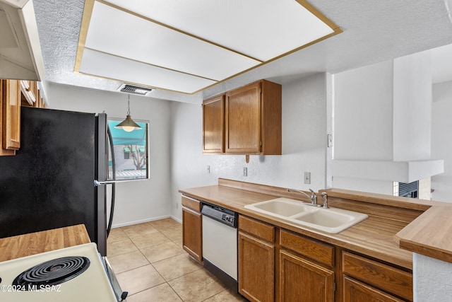 kitchen with dishwasher, black refrigerator, sink, hanging light fixtures, and a textured ceiling