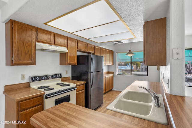 kitchen with black refrigerator, light wood-type flooring, sink, decorative light fixtures, and white electric stove