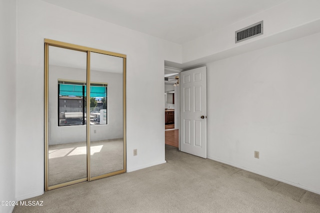 unfurnished bedroom featuring a closet and light colored carpet