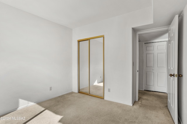 unfurnished bedroom with light colored carpet and a closet