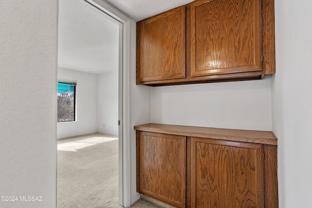 corridor with light colored carpet and a textured ceiling