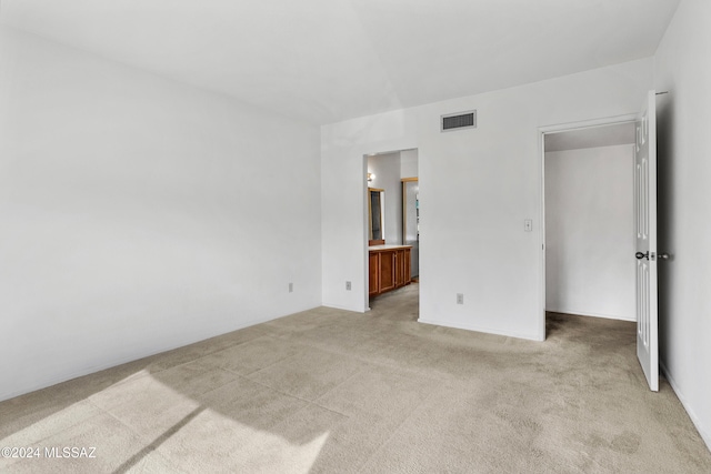 unfurnished bedroom with light colored carpet and ensuite bath