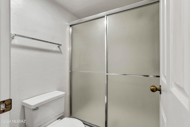 bathroom with toilet and a shower with shower door