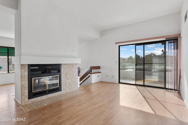 unfurnished living room with a tile fireplace, light hardwood / wood-style floors, and a healthy amount of sunlight