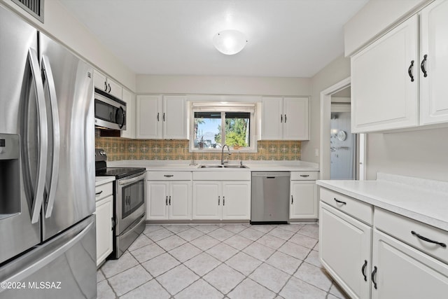 kitchen featuring backsplash, stainless steel appliances, sink, white cabinetry, and light tile patterned flooring