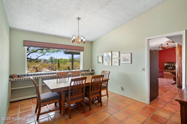 tiled dining area with a textured ceiling, ceiling fan with notable chandelier, and lofted ceiling