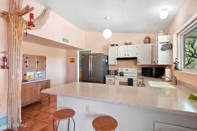 kitchen with stainless steel refrigerator, electric range, sink, kitchen peninsula, and a breakfast bar area