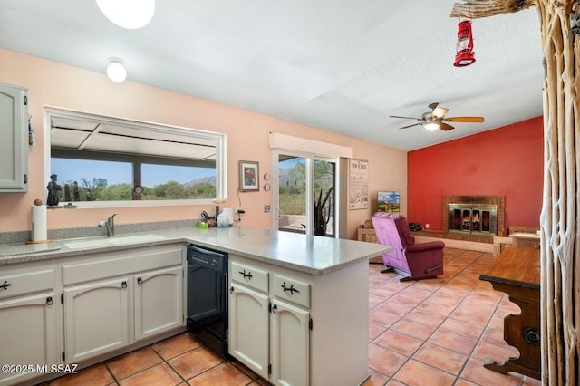 kitchen featuring sink, a brick fireplace, ceiling fan, black dishwasher, and kitchen peninsula