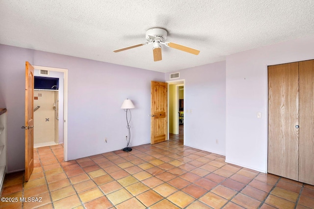 unfurnished bedroom with ceiling fan, a closet, light tile patterned flooring, and a textured ceiling