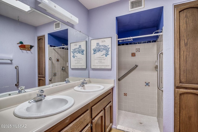 bathroom with tiled shower and vanity