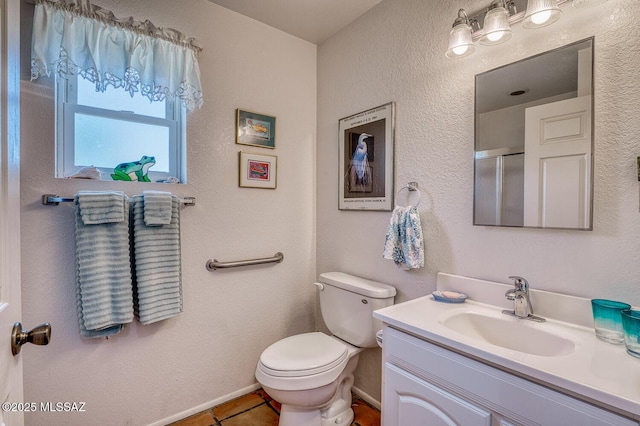 bathroom featuring tile patterned flooring, vanity, a shower with shower door, and toilet