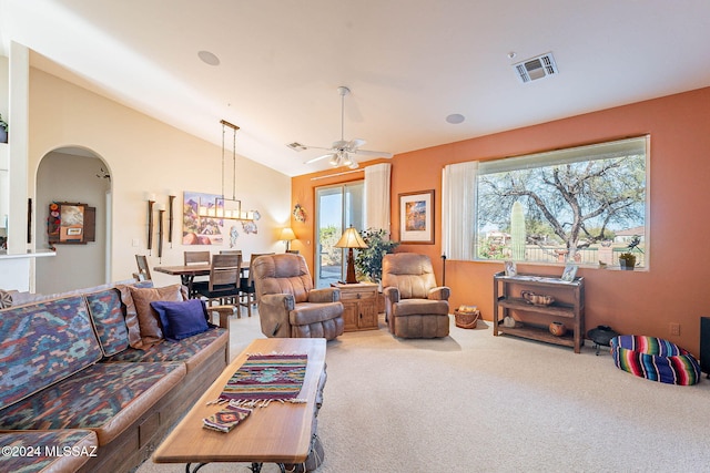 carpeted living area featuring vaulted ceiling, arched walkways, visible vents, and a ceiling fan