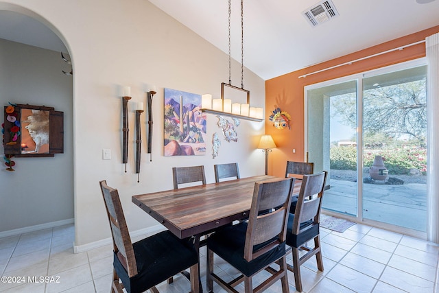 dining area with arched walkways, light tile patterned floors, visible vents, vaulted ceiling, and baseboards