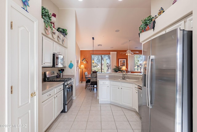 kitchen featuring light tile patterned floors, a peninsula, appliances with stainless steel finishes, and white cabinets