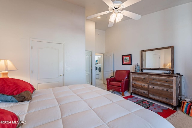 bedroom with a towering ceiling, carpet, a ceiling fan, and independent washer and dryer