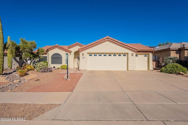 view of front facade with a garage, a tiled roof, concrete driveway, and stucco siding