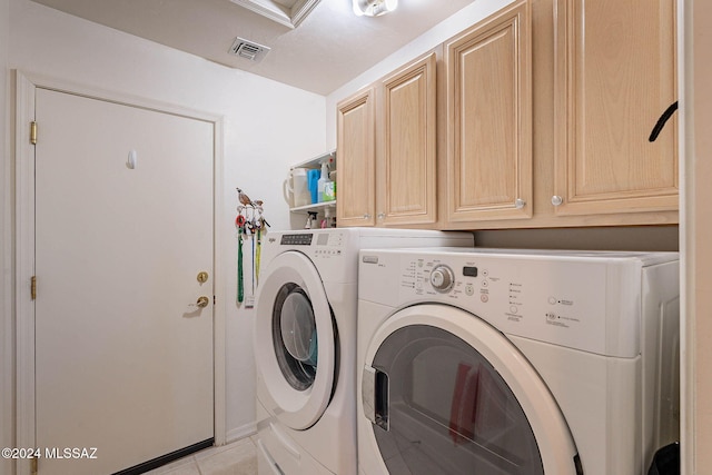 laundry area featuring washing machine and dryer, cabinet space, visible vents, and light tile patterned floors