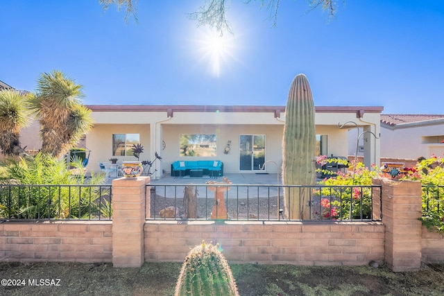 view of front of home with stucco siding, fence, and a patio