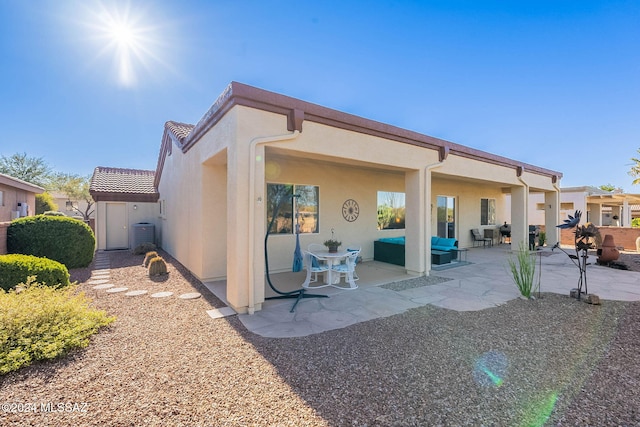 back of house featuring outdoor lounge area, a patio area, and stucco siding