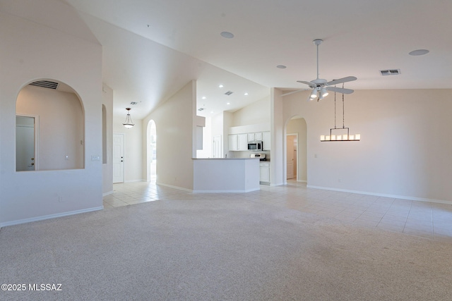 unfurnished living room featuring arched walkways, visible vents, light carpet, light tile patterned flooring, and high vaulted ceiling