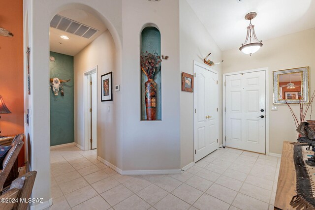 entryway with light tile patterned floors, arched walkways, visible vents, and baseboards