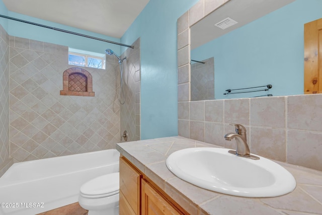 full bathroom with vanity, backsplash, tiled shower / bath combo, and toilet