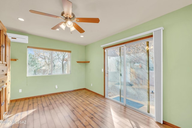 spare room with ceiling fan, light hardwood / wood-style floors, and an AC wall unit