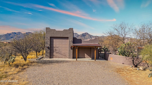 pueblo-style house featuring a garage and a mountain view