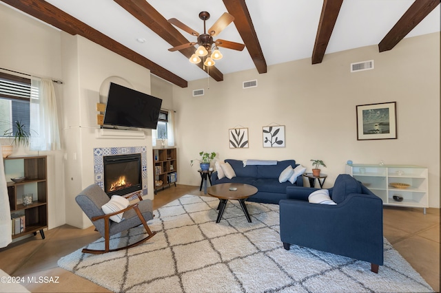 living room featuring beamed ceiling, plenty of natural light, ceiling fan, and a fireplace