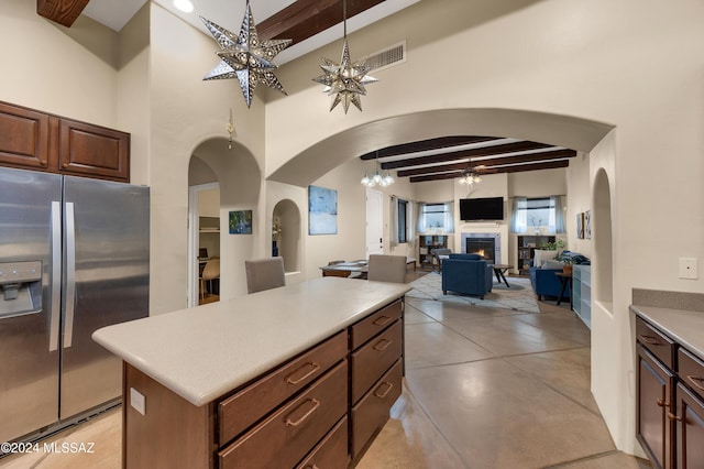 kitchen featuring ceiling fan with notable chandelier, beam ceiling, decorative light fixtures, stainless steel fridge with ice dispenser, and a center island