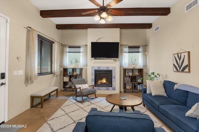 living room featuring beam ceiling, light tile patterned floors, ceiling fan, and a tiled fireplace