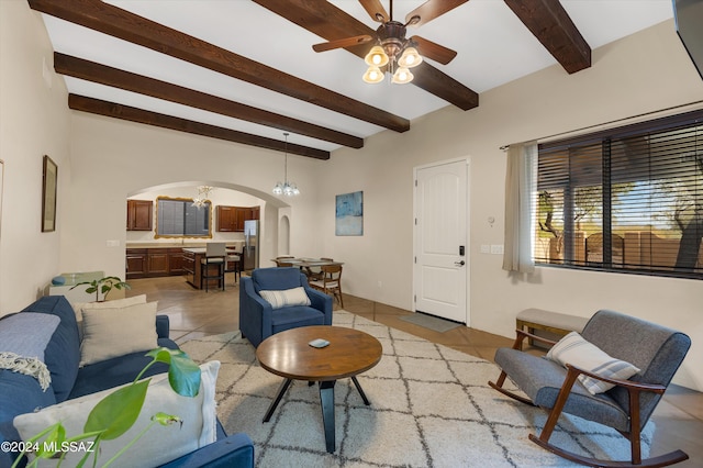 living room featuring beamed ceiling, light tile patterned floors, and ceiling fan with notable chandelier