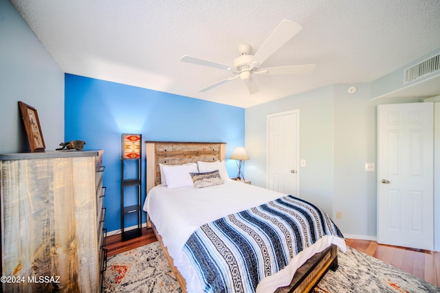 bedroom with hardwood / wood-style floors, a textured ceiling, and ceiling fan