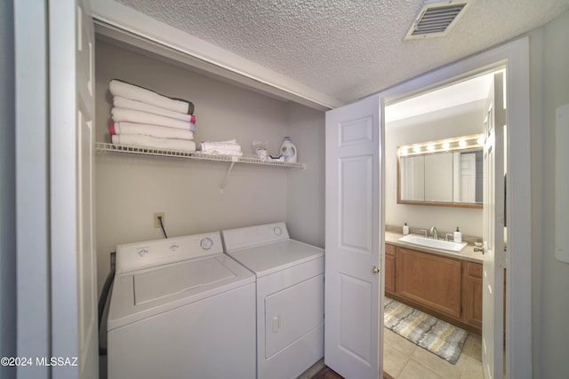 laundry room featuring independent washer and dryer, a textured ceiling, light tile patterned floors, and sink