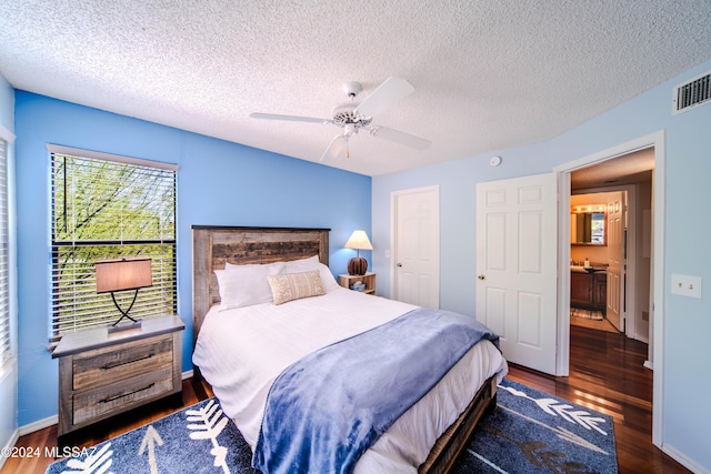 bedroom featuring ceiling fan, dark hardwood / wood-style flooring, ensuite bathroom, and a textured ceiling