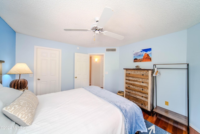 bedroom featuring ceiling fan, dark hardwood / wood-style flooring, and a textured ceiling